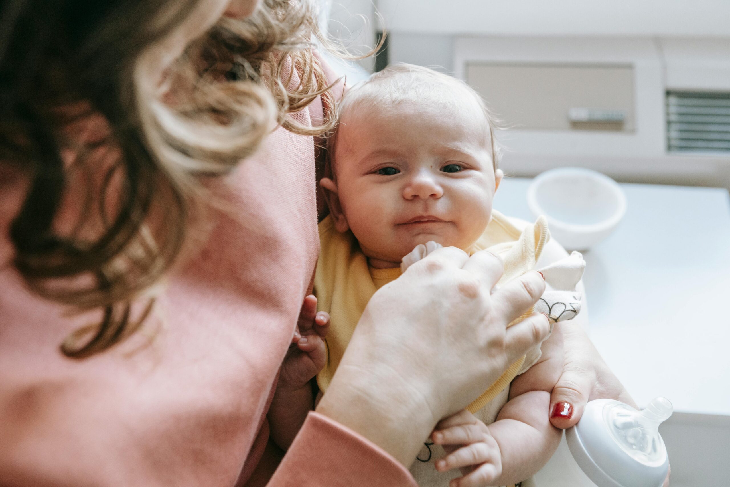 A mother gently cradles her newborn baby indoors, showcasing love and tenderness.
